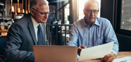 two men standing over paper work
